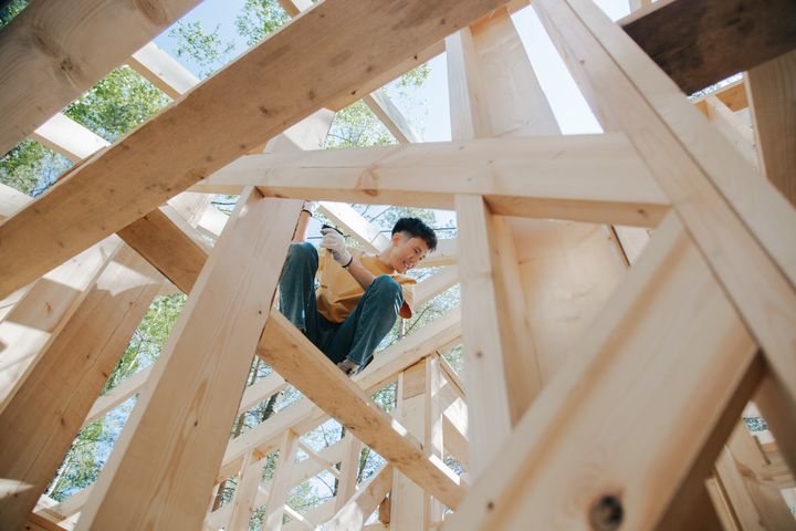 A carpenter working among timber framing at a real home construction site.