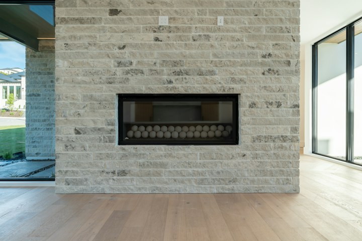 Natural wood flooring beside a contemporary stone fireplace.