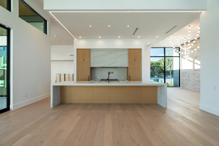 A real light-oak kitchen with a stone island, fitted cabinetry, and black-framed windows.