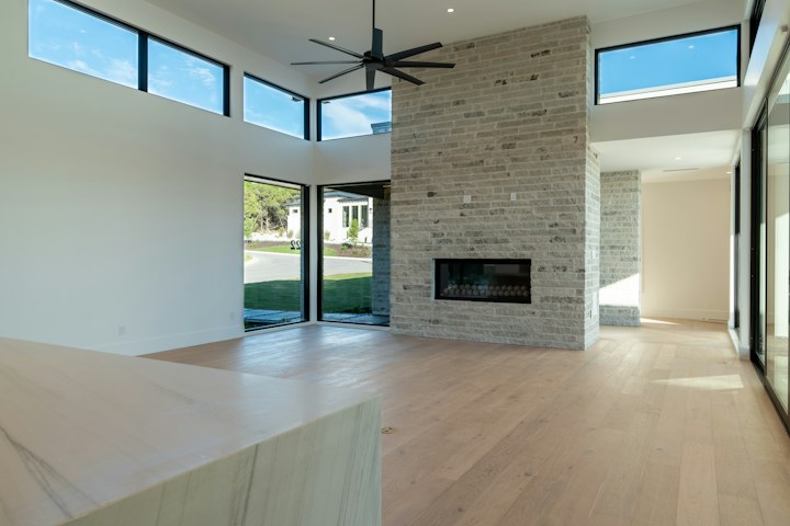 A real contemporary living room with wood flooring, a stone fireplace, and large windows.
